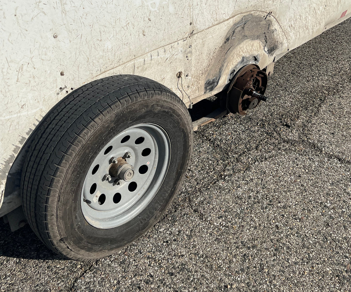 Trailer with one wheel missing, the bare spindle exposed behind the remaining tire